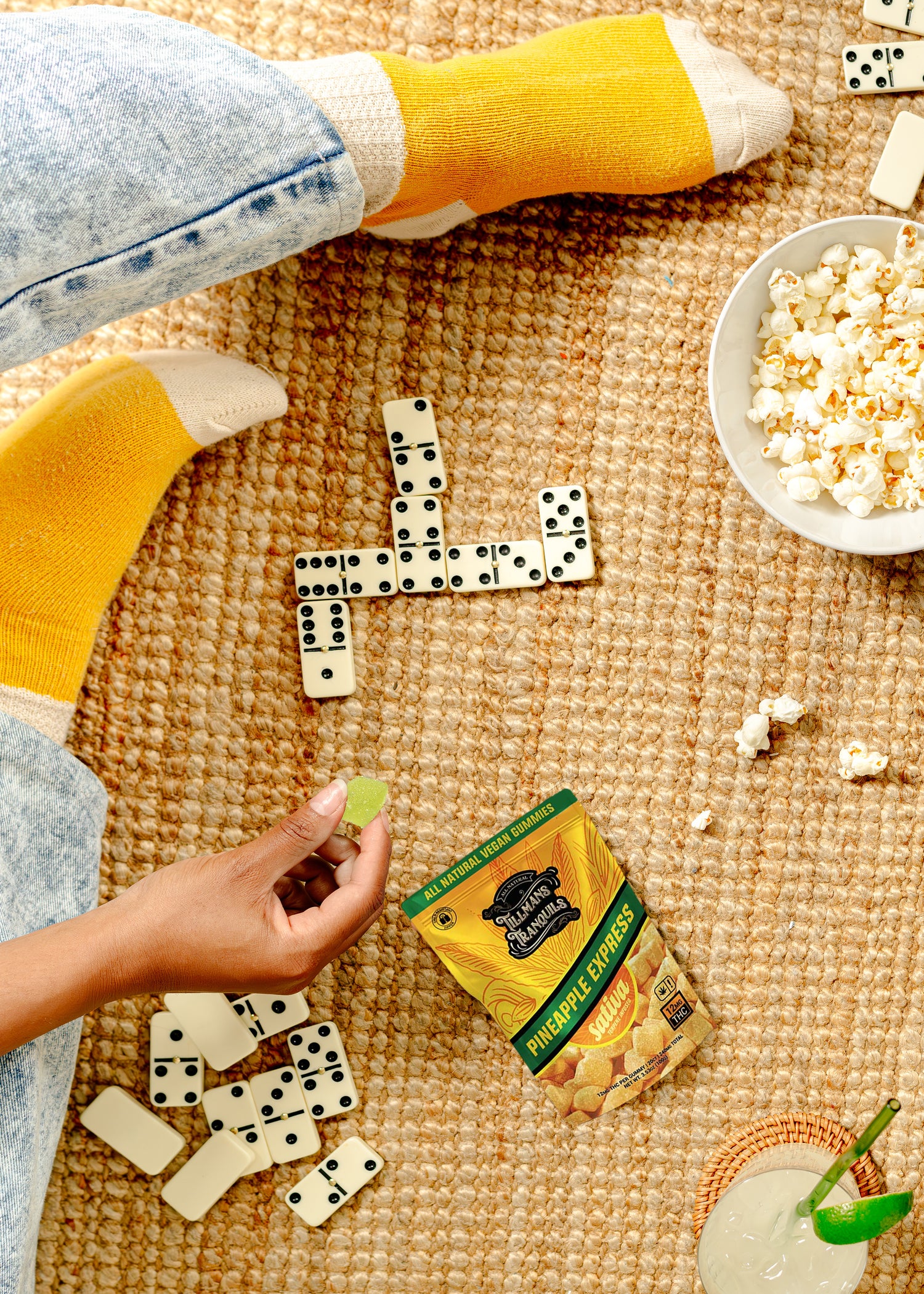 Person playing dominoes with snacks on a textured surface
